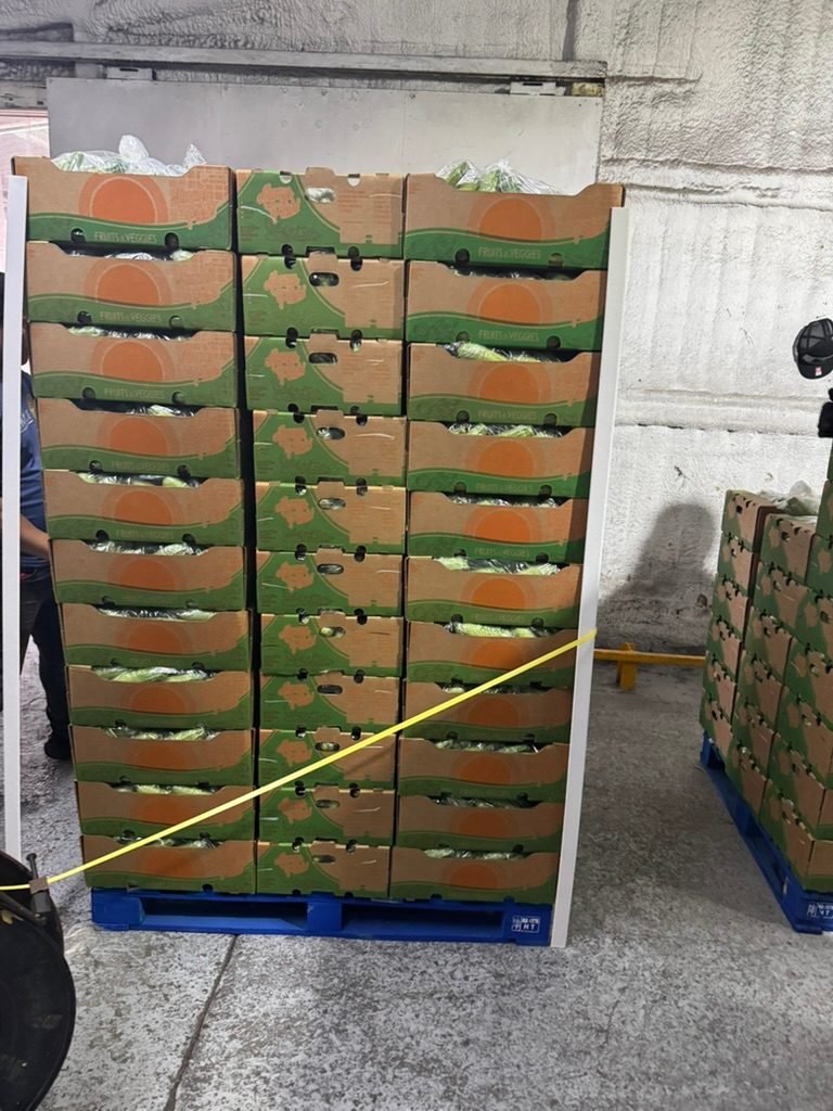 A strapped pallet of packed produce boxes in a cold room